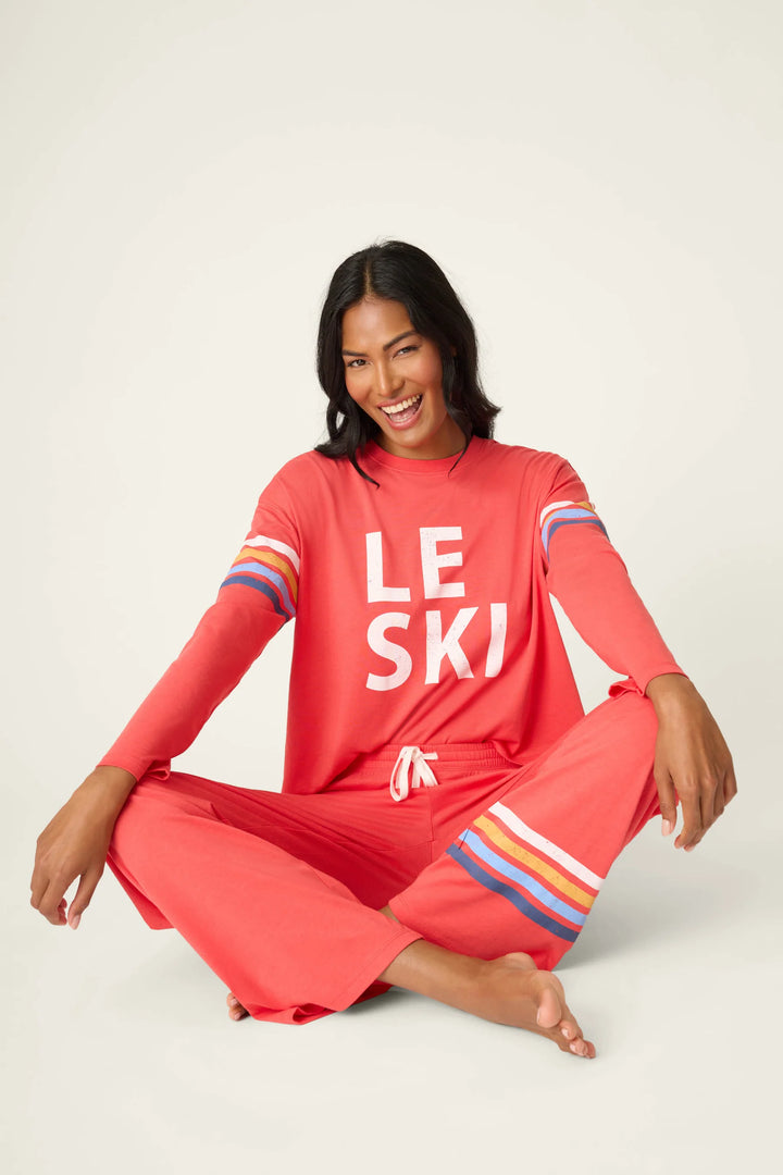Woman wearing a red 'LE SKI' outfit sitting on a white background