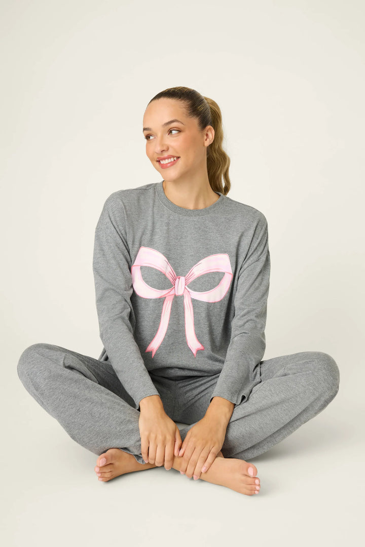 Woman wearing gray pajamas with a pink bow design on a white background