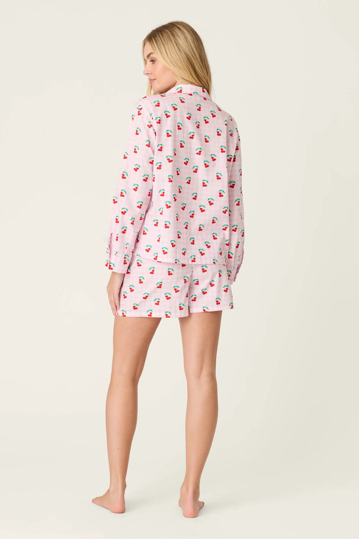 Woman wearing a pink pajama set with cherry pattern on a white background