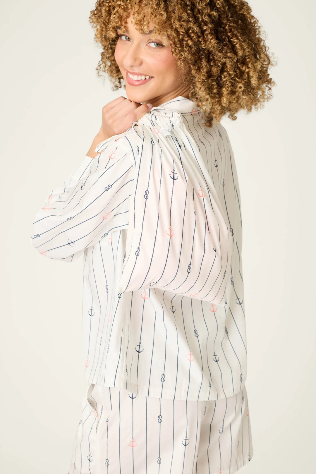 Woman wearing a long, light-colored striped shirt with a plain background