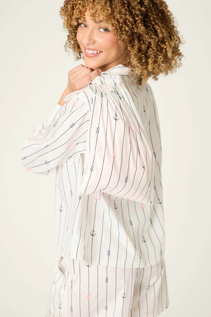 Woman wearing a long, light-colored striped shirt with a plain background