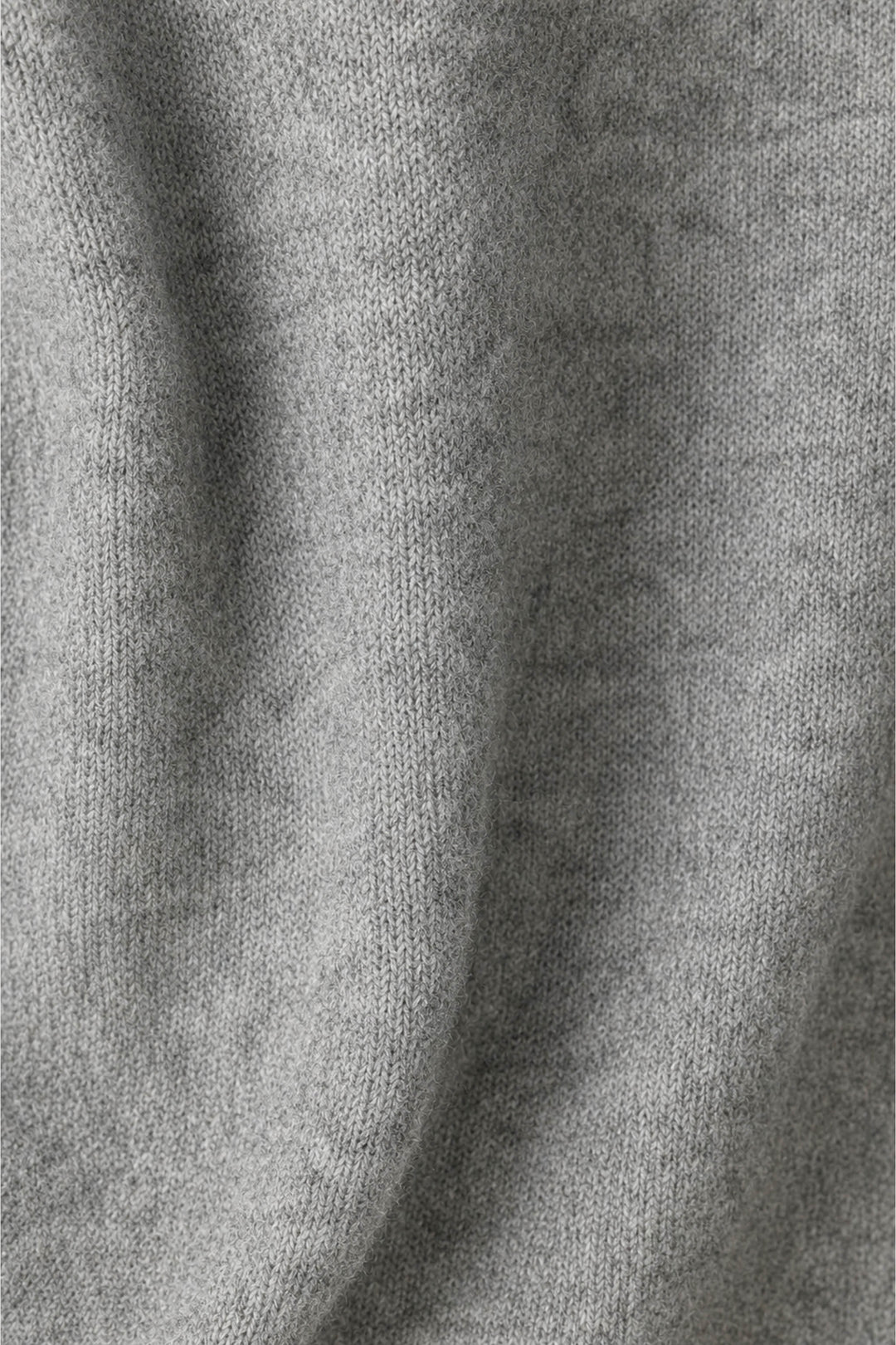A close-up of a light gray knit fabric with soft folds and a fine ribbed texture.