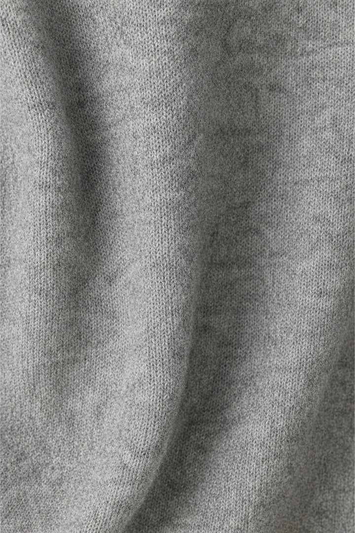 A close-up of a light gray knit fabric with soft folds and a fine ribbed texture.