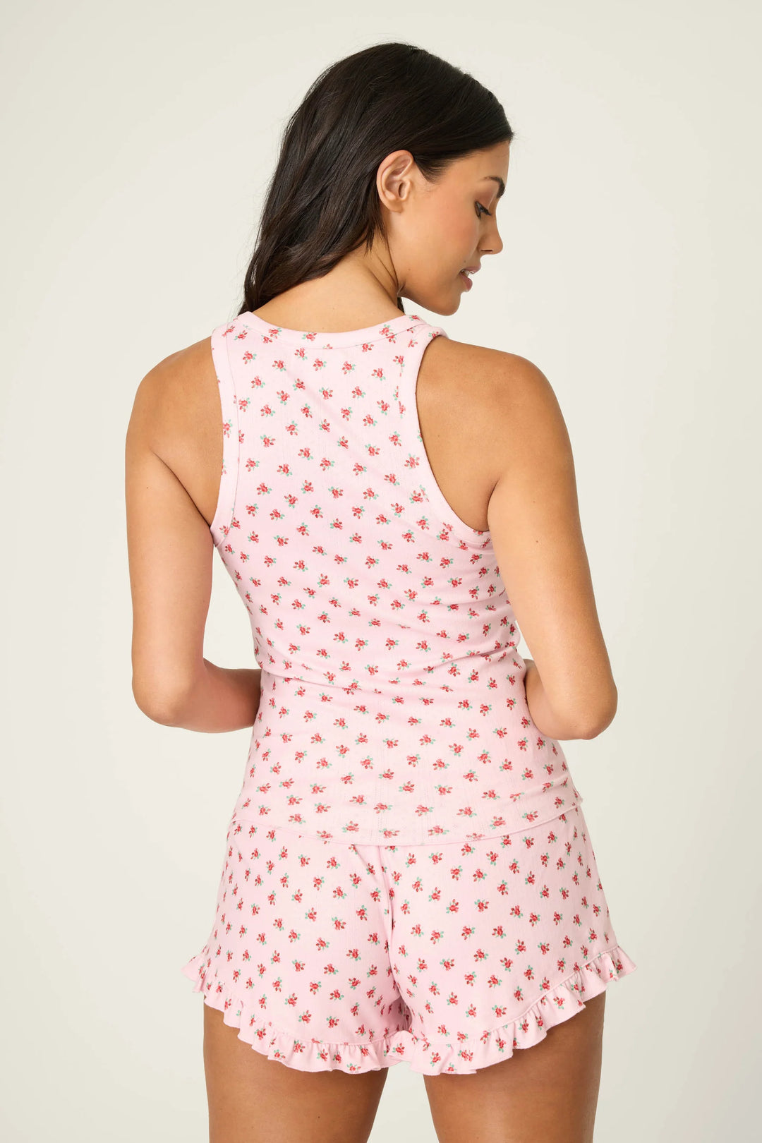 Woman wearing a pink floral pajama set against a plain background