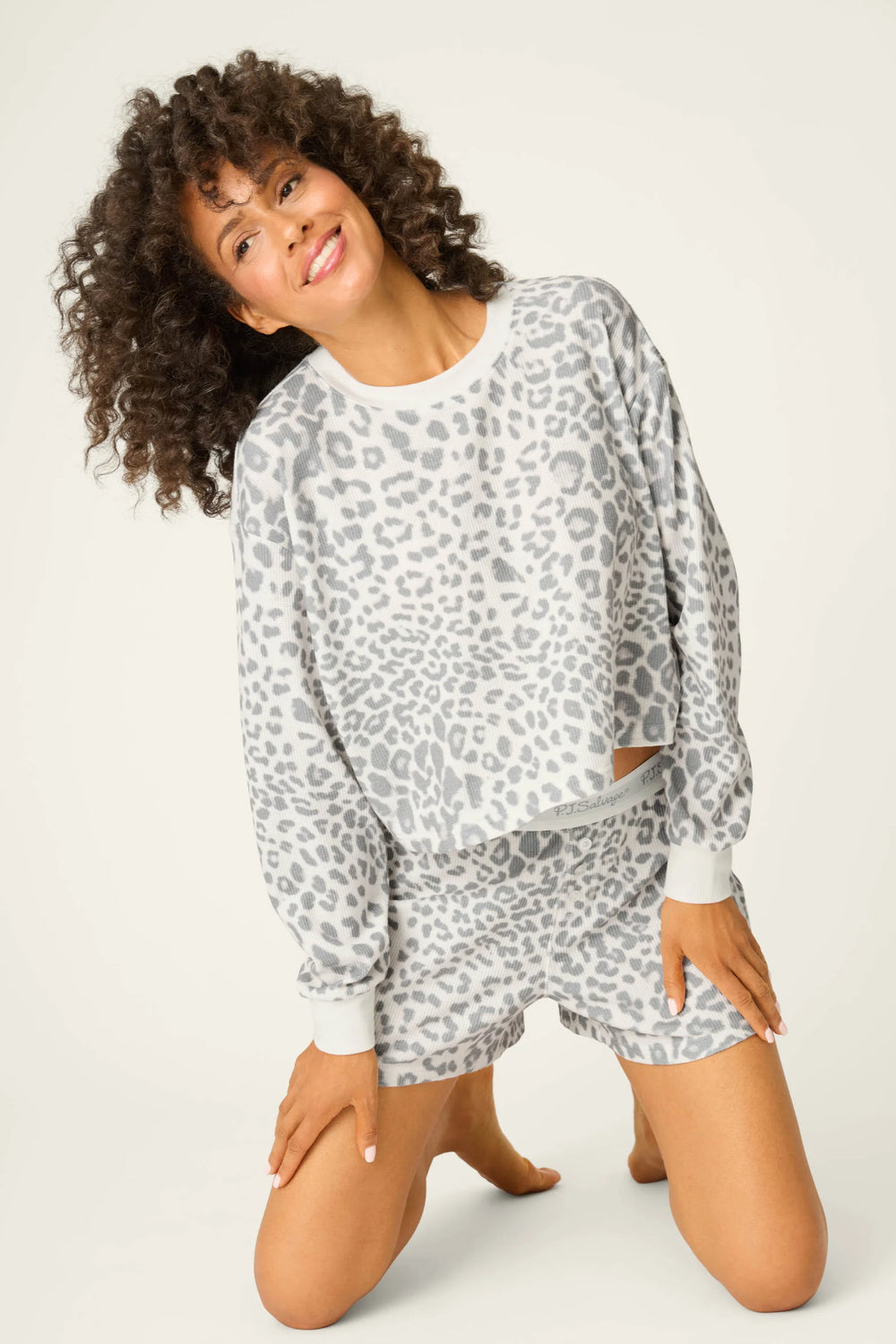 Woman wearing a gray leopard print pajama set on a white background