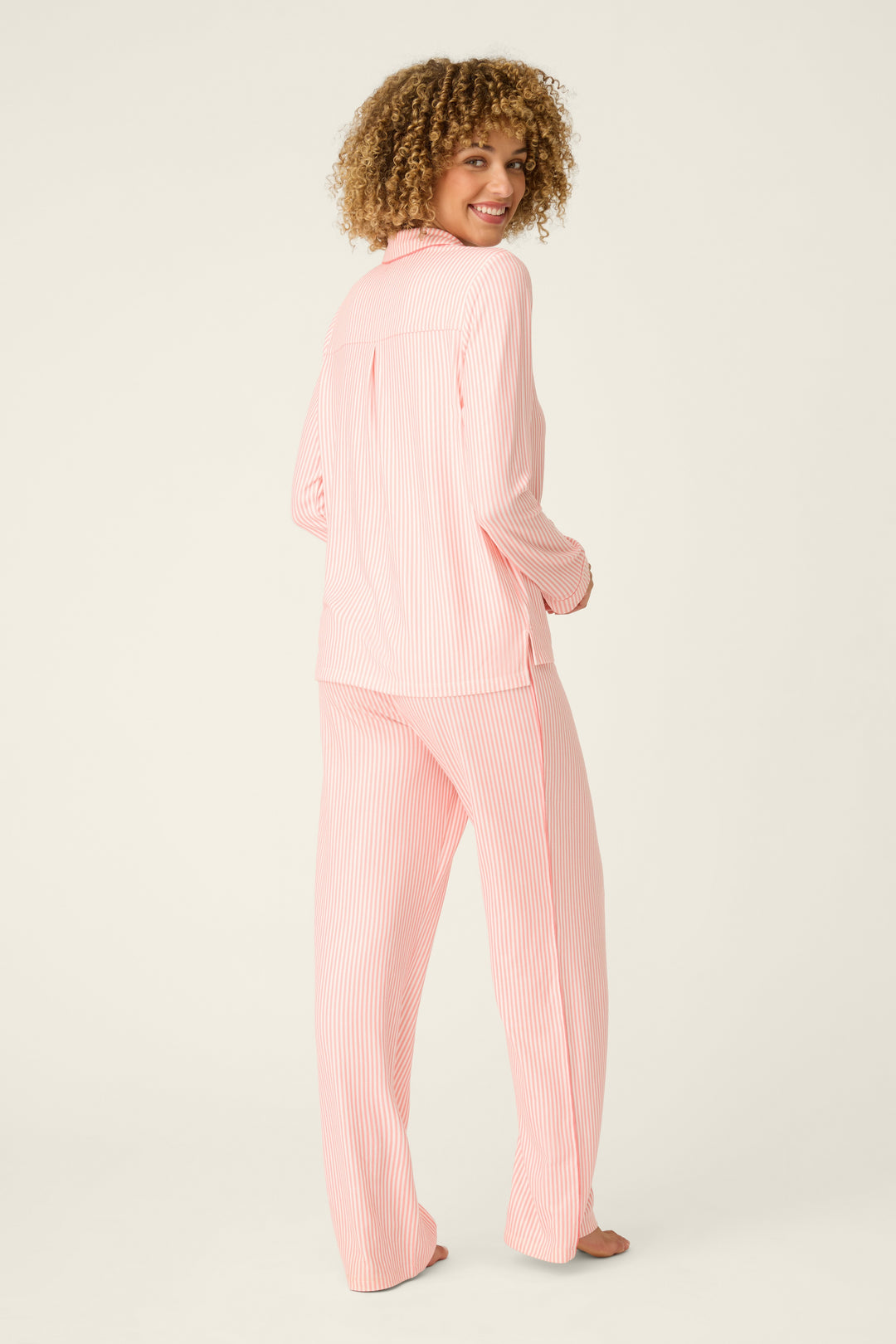 Woman wearing a pink striped pajama set on a white background