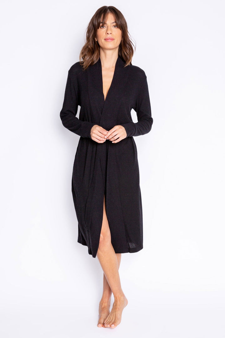 A woman modeling a black long-sleeve wrap robe with a V-neck and front slit, standing against a plain white studio background.