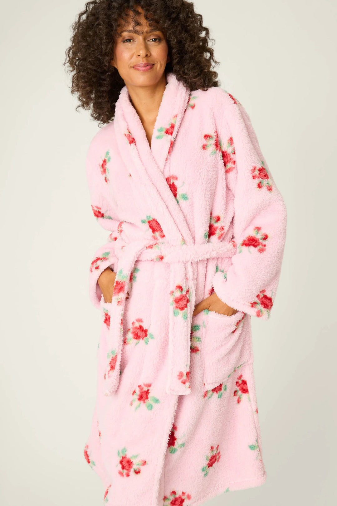 Woman wearing a pink floral robe against a plain background
