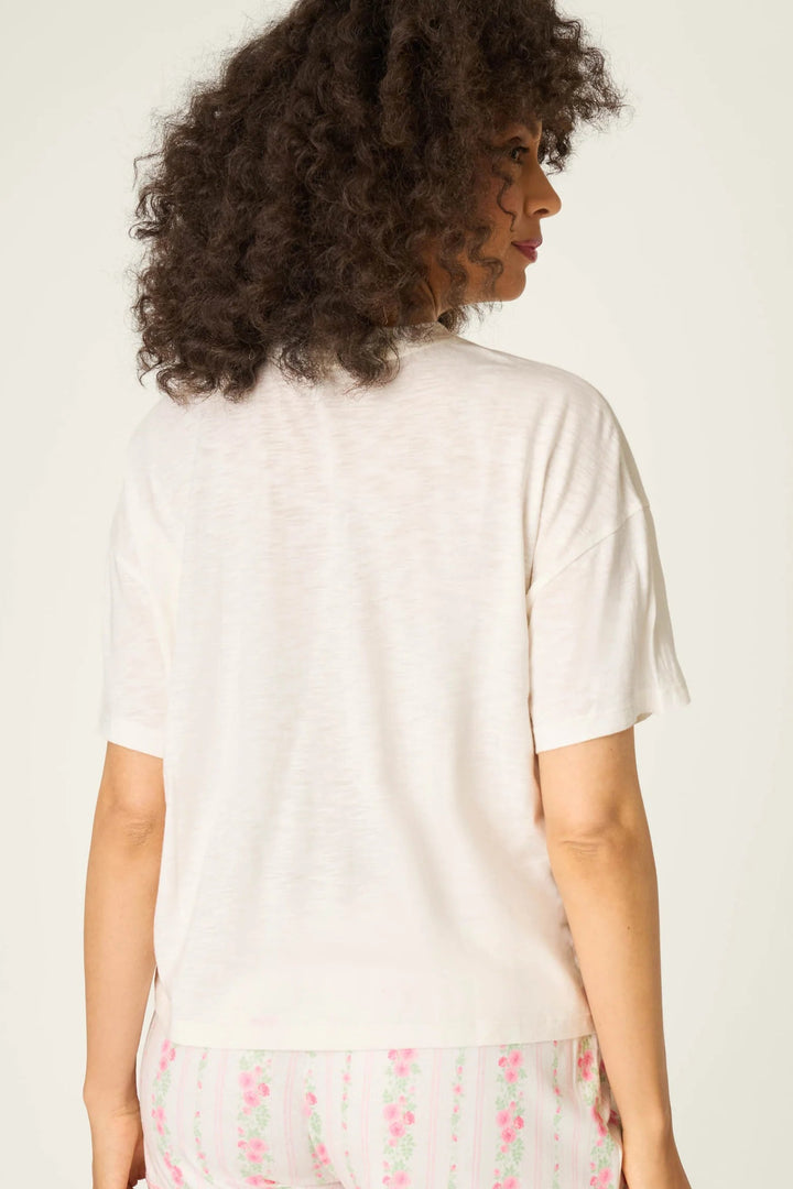 Woman wearing a white t-shirt and pink floral pants on a plain background