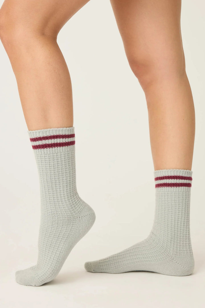 Gray socks with red stripes worn by a person on a light background