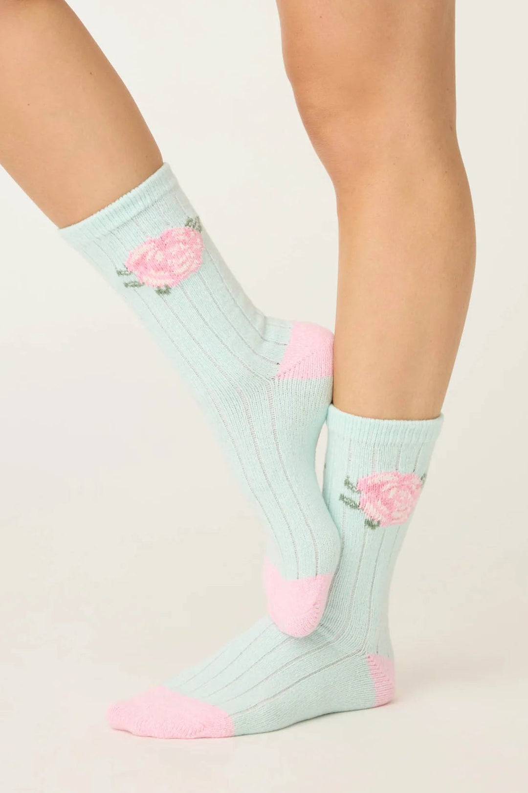 Light blue socks with pink flamingo designs worn by a person on a plain background