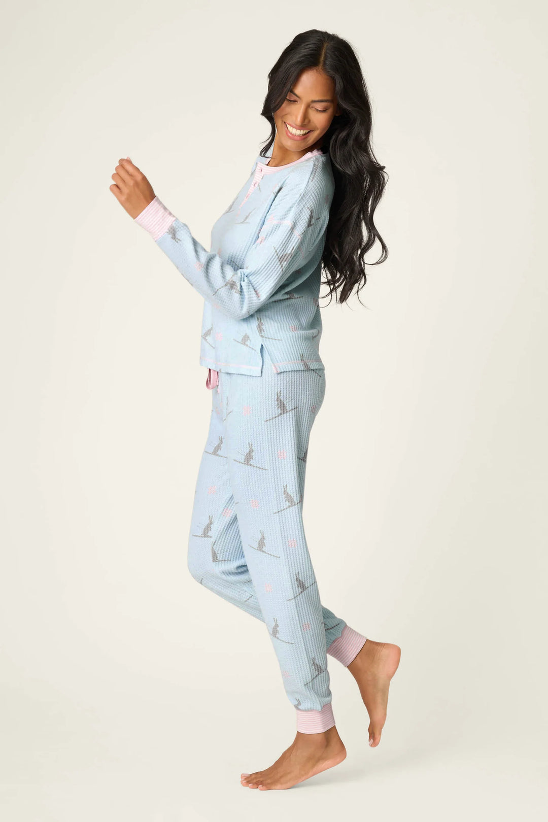 Woman wearing light blue pajama set with ski bunny pattern on a white background