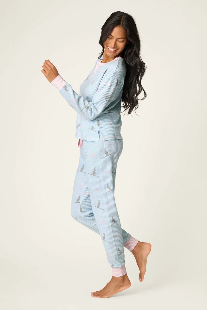 Woman wearing light blue pajama set with ski bunny pattern on a white background