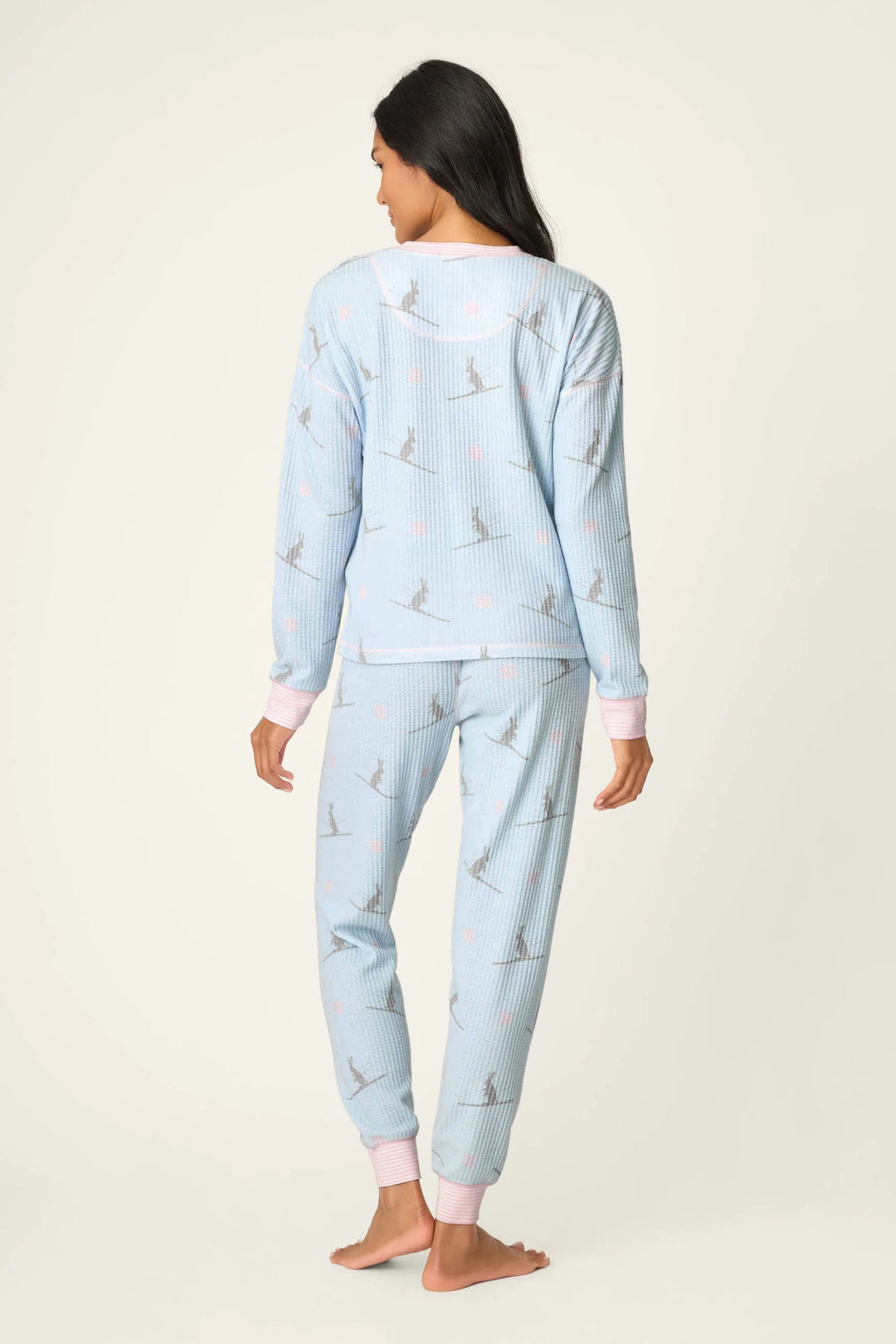 Woman wearing light blue pajama set with ski bunny pattern on a white background