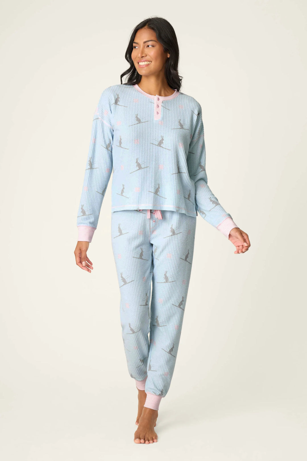 Woman wearing light blue pajama set with ski bunny pattern on a white background