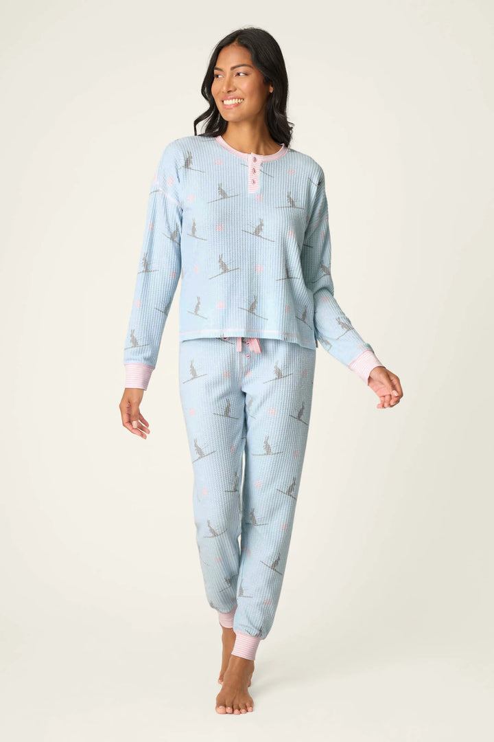 Woman wearing light blue pajama set with ski bunny pattern on a white background