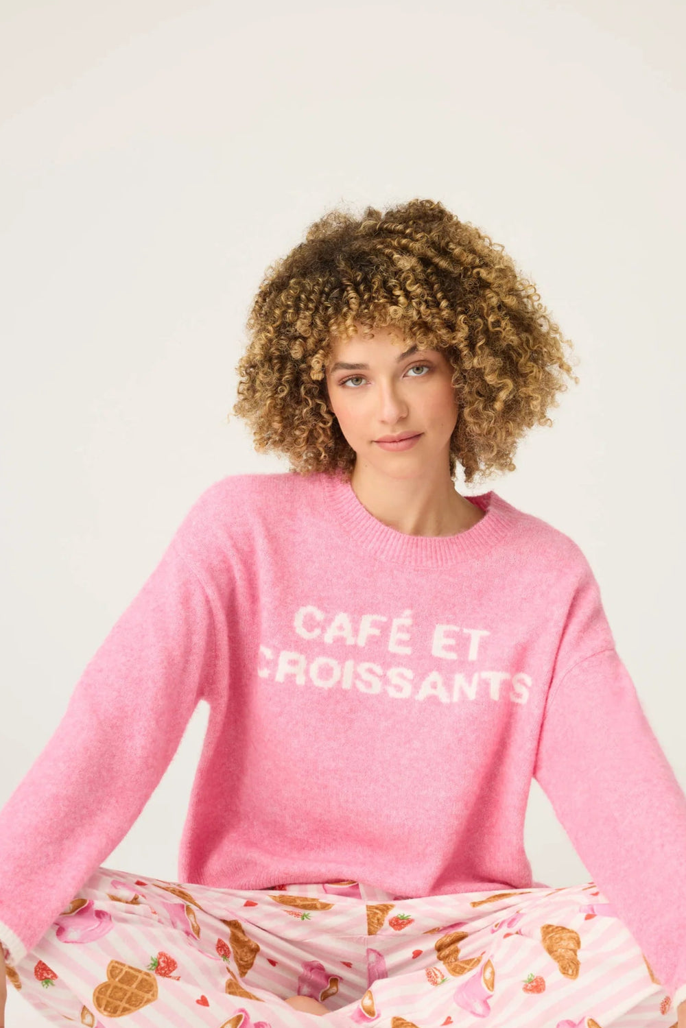 Person wearing a pink sweater with text on a white background
