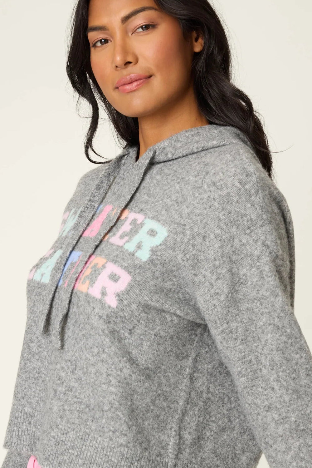 Woman wearing a gray hoodie with colorful text and light blue shorts with dog design on a white background