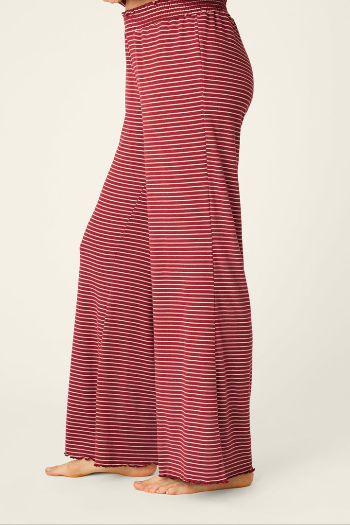 A person wearing a matching two-piece loungewear set with a red and white horizontal stripe pattern, shown from the waist down against a plain light beige studio background.