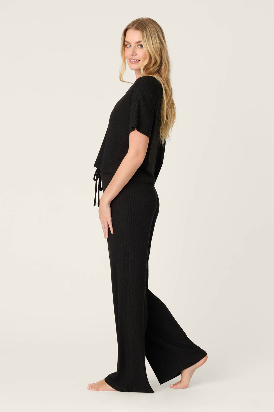 Woman wearing a black outfit with wide-leg pants on a white background
