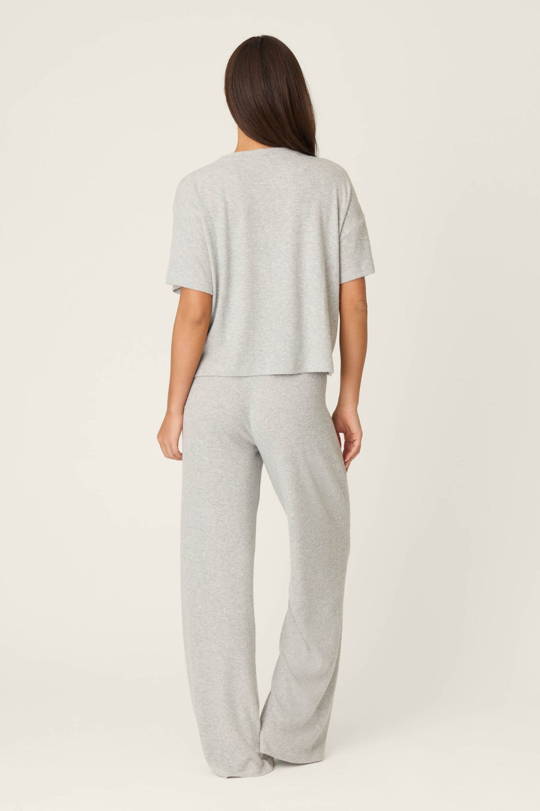 Person wearing a gray t-shirt and pants on a white background