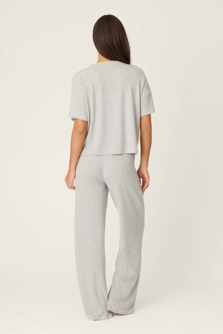 Person wearing a gray t-shirt and pants on a white background
