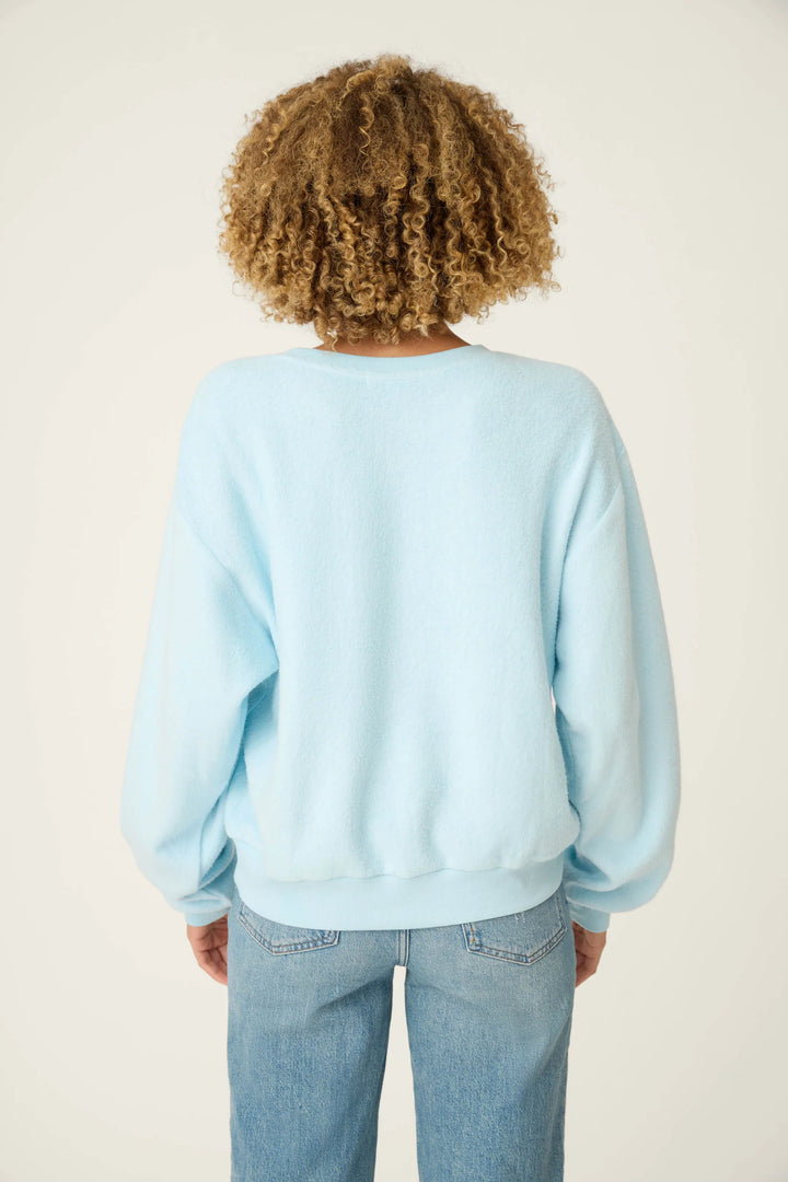 Person wearing a light blue sweatshirt and jeans on a plain background