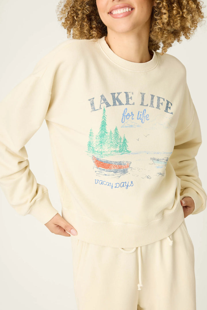 Person wearing a cream sweatshirt with 'Lake Life' graphic design on a plain background
