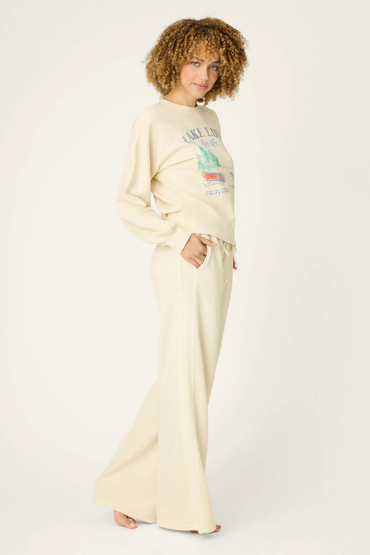 Woman wearing a cream-colored sweatshirt and pants on a white background