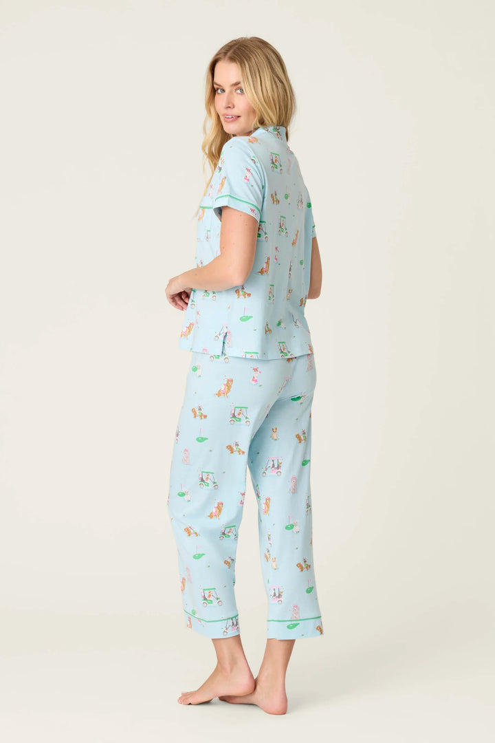 Woman wearing a light blue pajama set with dog print on a plain background
