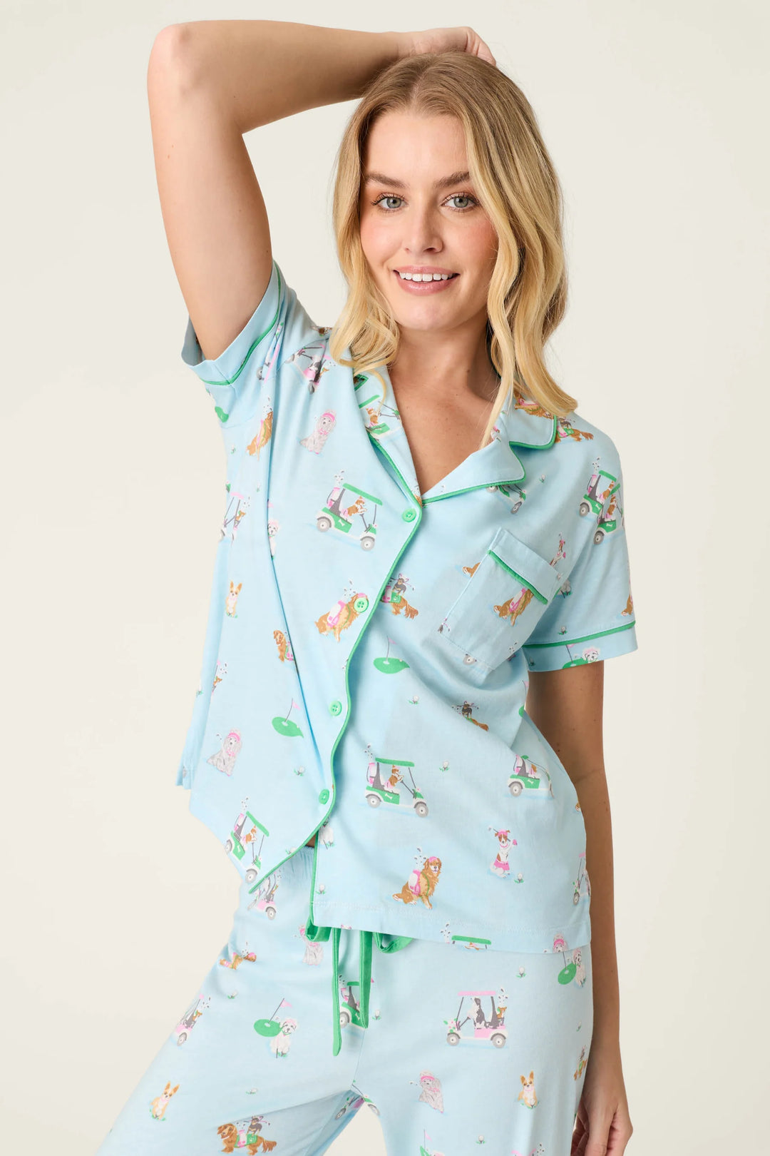 Woman wearing a light blue pajama set with dog print on a plain background