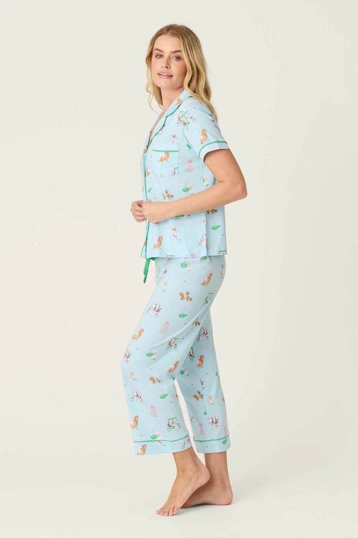 Woman wearing a light blue pajama set with animal prints on a white background