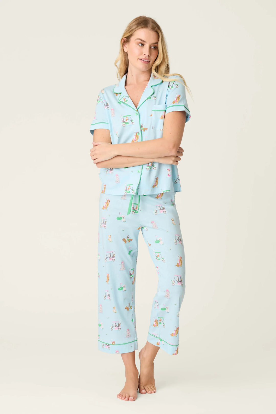 Woman wearing a light blue pajama set with dog print on a plain background