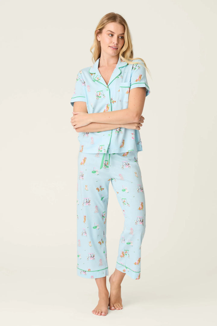 Woman wearing a light blue pajama set with dog print on a plain background