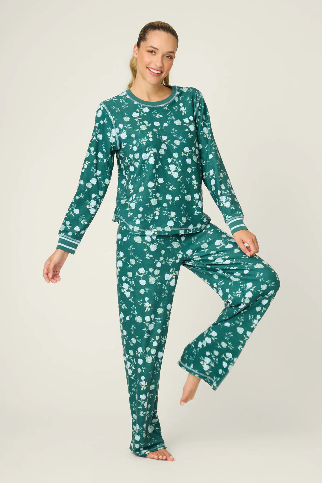 Woman wearing a green floral pajama set on a white background