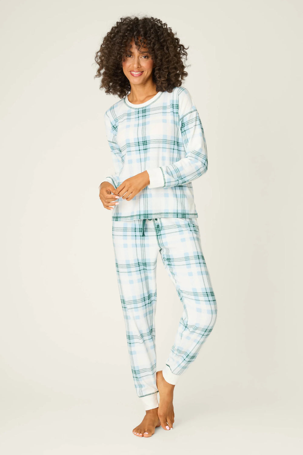Woman wearing a blue and white plaid pajama set on a plain background