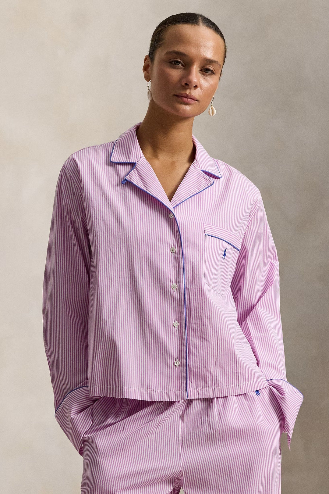 Woman wearing a pink striped polo ralph lauren pajama set against a neutral background
