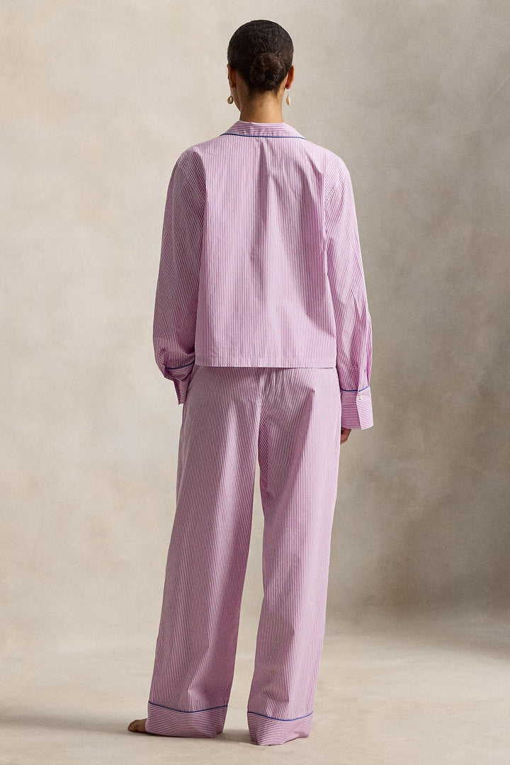 Woman wearing a pink striped polo ralph lauren pajama set against a neutral background
