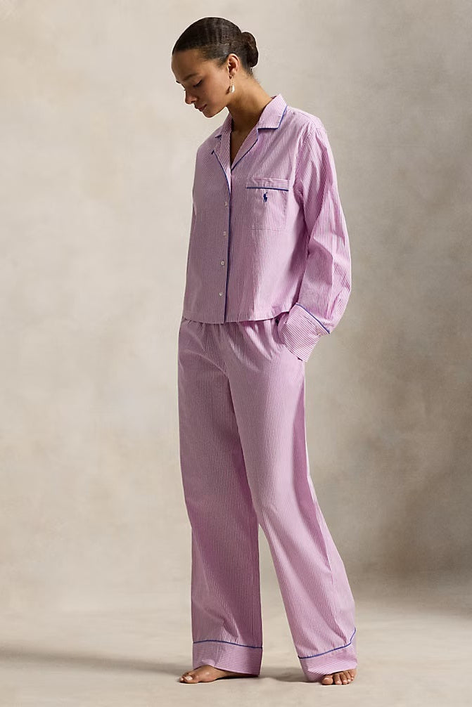 Woman wearing a pink striped polo ralph lauren pajama set against a neutral background