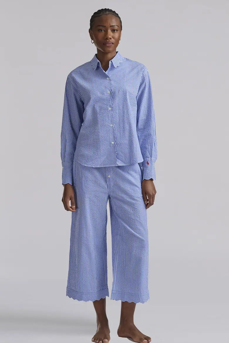Person wearing a blue striped pajama set on a plain background