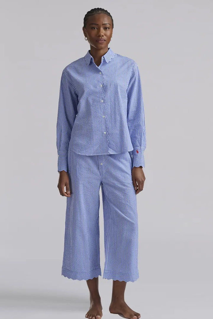 Person wearing a blue striped pajama set on a plain background