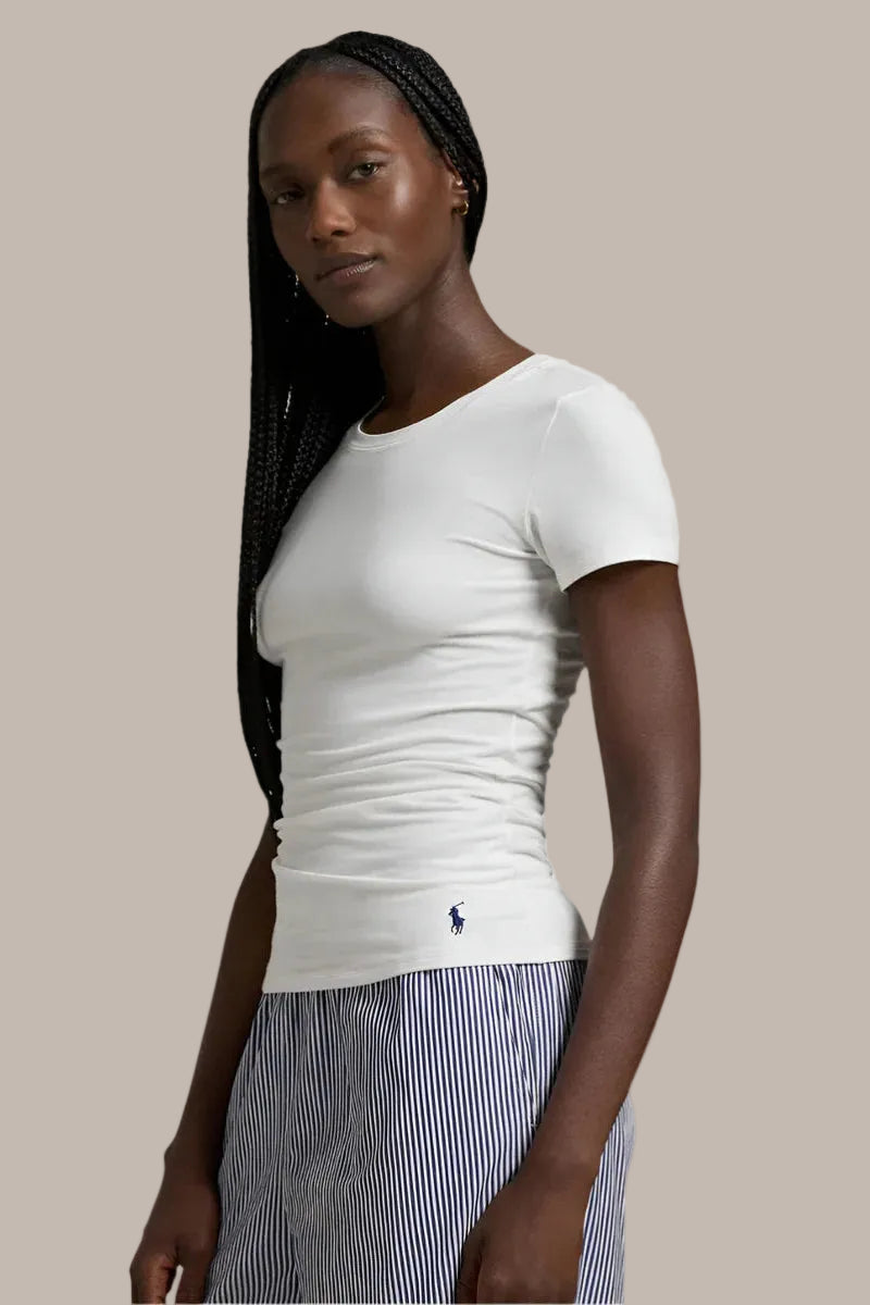 Woman wearing a white t-shirt with a visible polo ralph lauren brand logo on a plain background