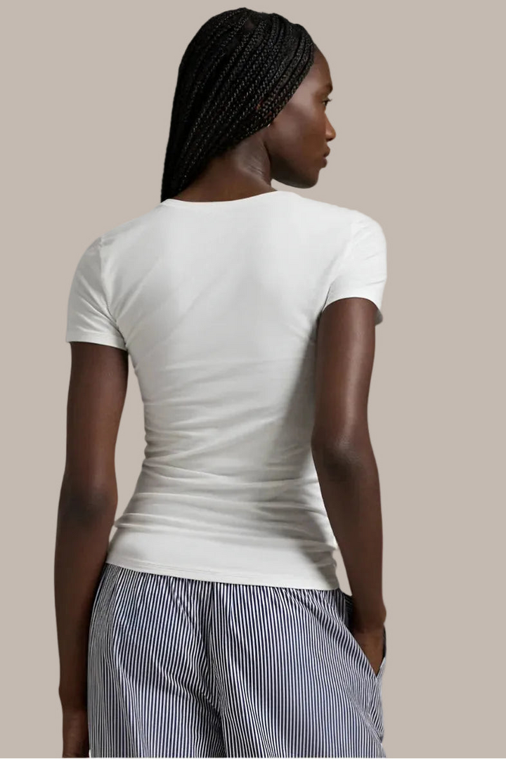 Woman wearing a polo white t-shirt and striped pants on a plain background