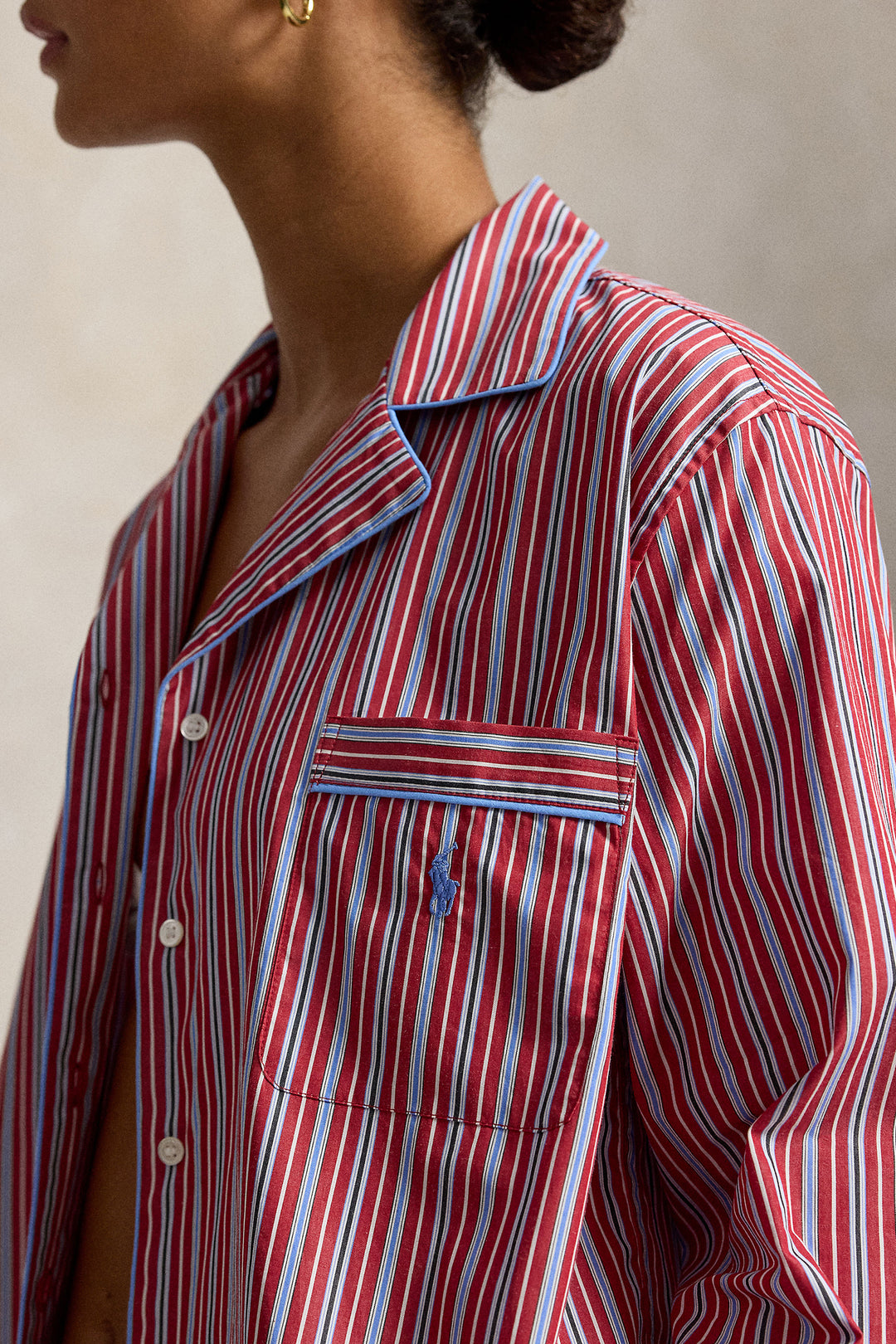 woman wearing a red blue striped pajama set with blue piping trim. Buttoned top with notch collar and full length pant with elastic waistband. 