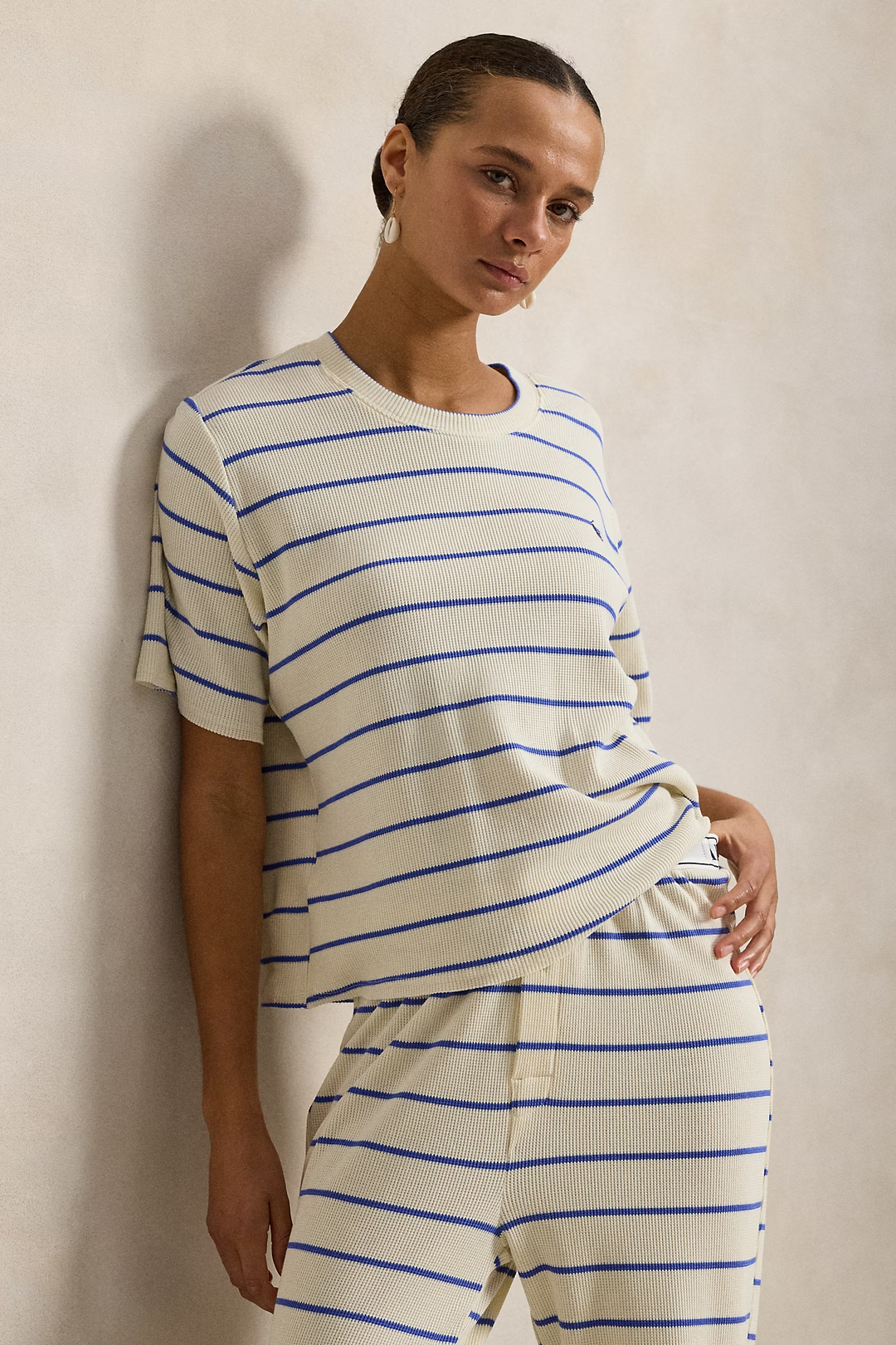 Person wearing a white and blue striped outfit against a plain background