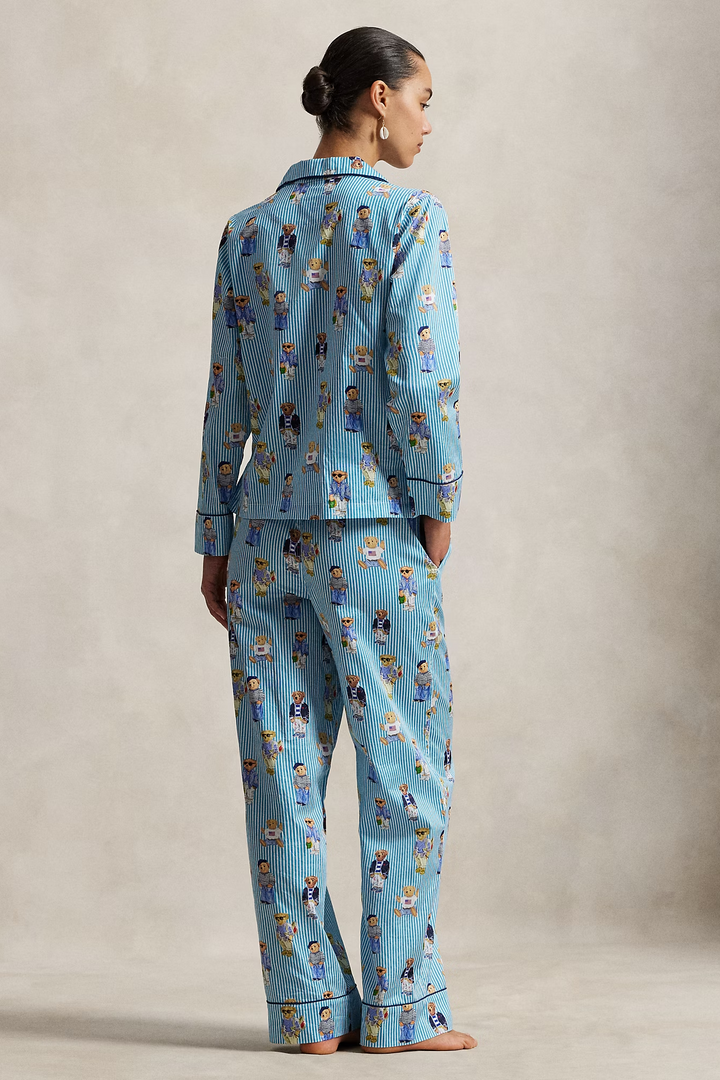 Woman wearing a polo ralph lauren blue striped pajama set with polo bear pattern on a neutral background