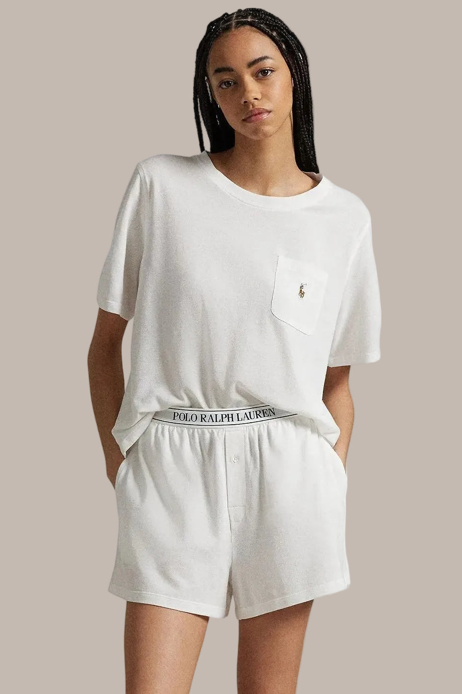 Person wearing a white t-shirt and shorts with Ralph Lauren logo on a plain background