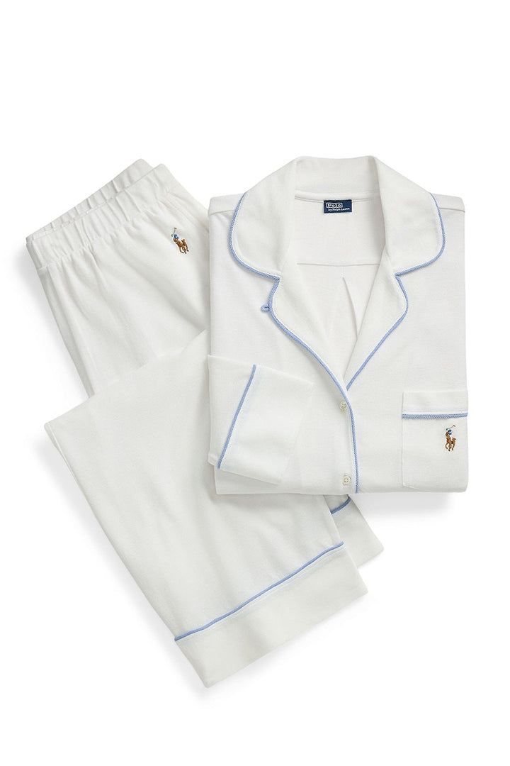 A folded white pajama set with light blue piping and small embroidered polo player logos, shown on a clean white background.