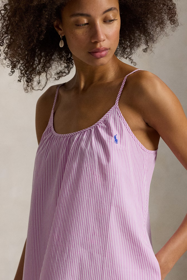 Woman wearing a pink striped dress with a visible Polo brand logo against a neutral background