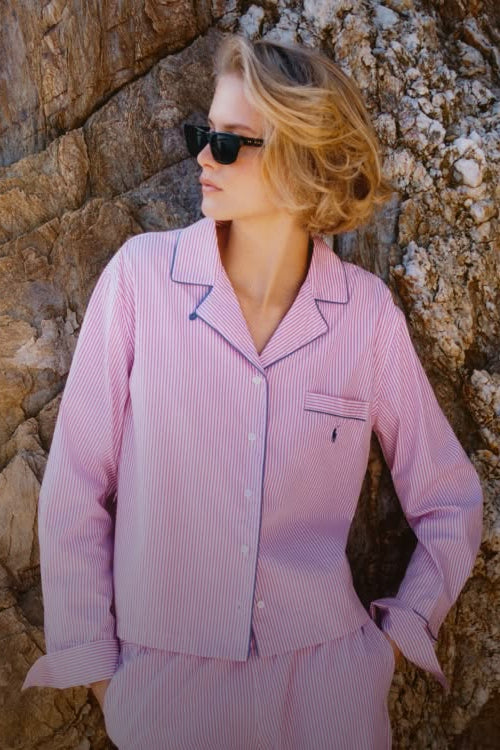 Woman wearing a pink striped pajama set against a rocky background